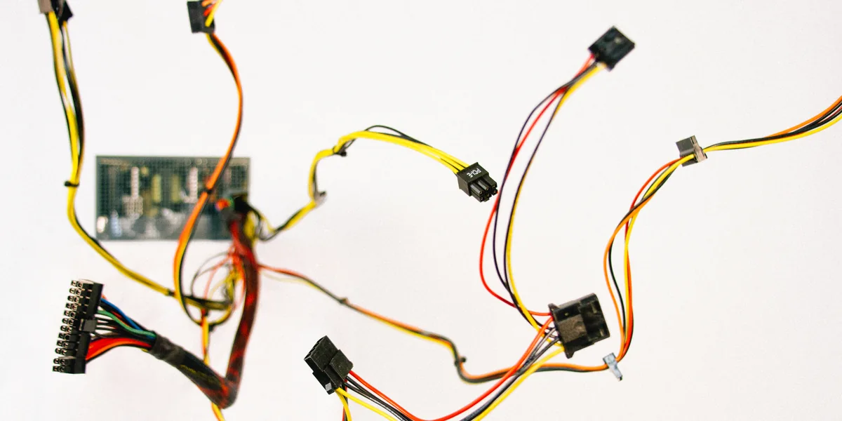 Fascio di cavi colorati e un piccolo circuito su sfondo bianco, connettori sparsi in tutte le direzioni