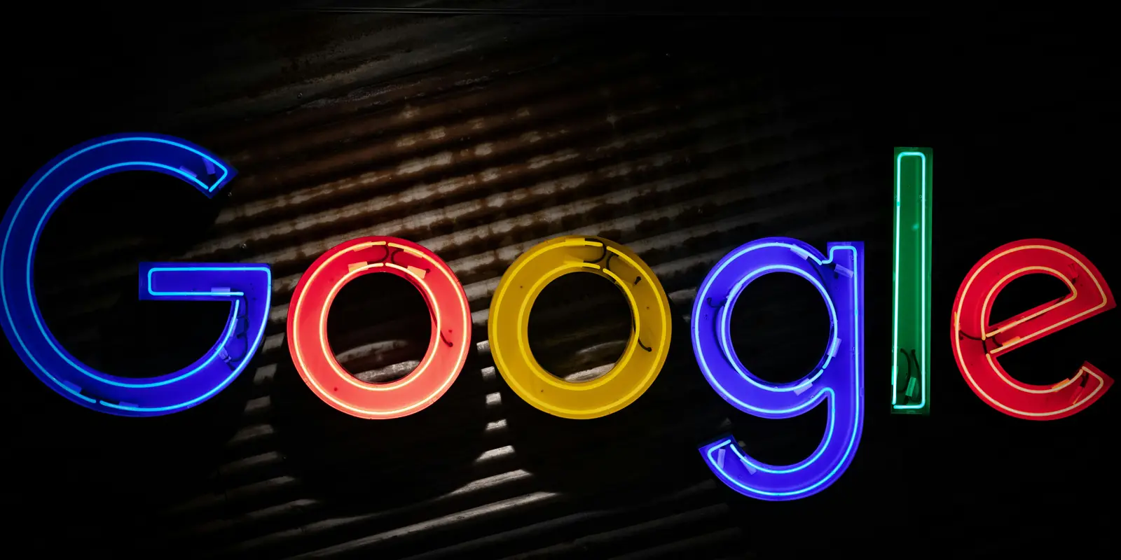 Sigla Google în tuburi de neon colorate, pe un perete metalic întunecat
