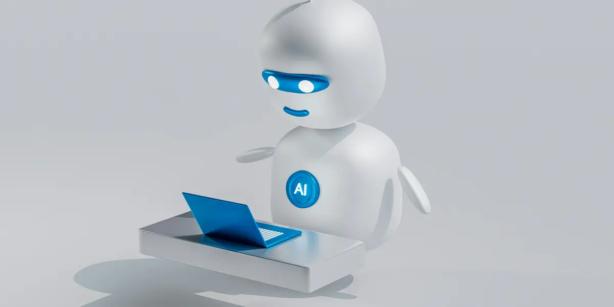Un robot alb stilizat, cu ochi luminoși albaștri și o insignă rotundă cu literele AI pe piept, stând în fața unui laptop albastru miniatural pe un fundal gri deschis