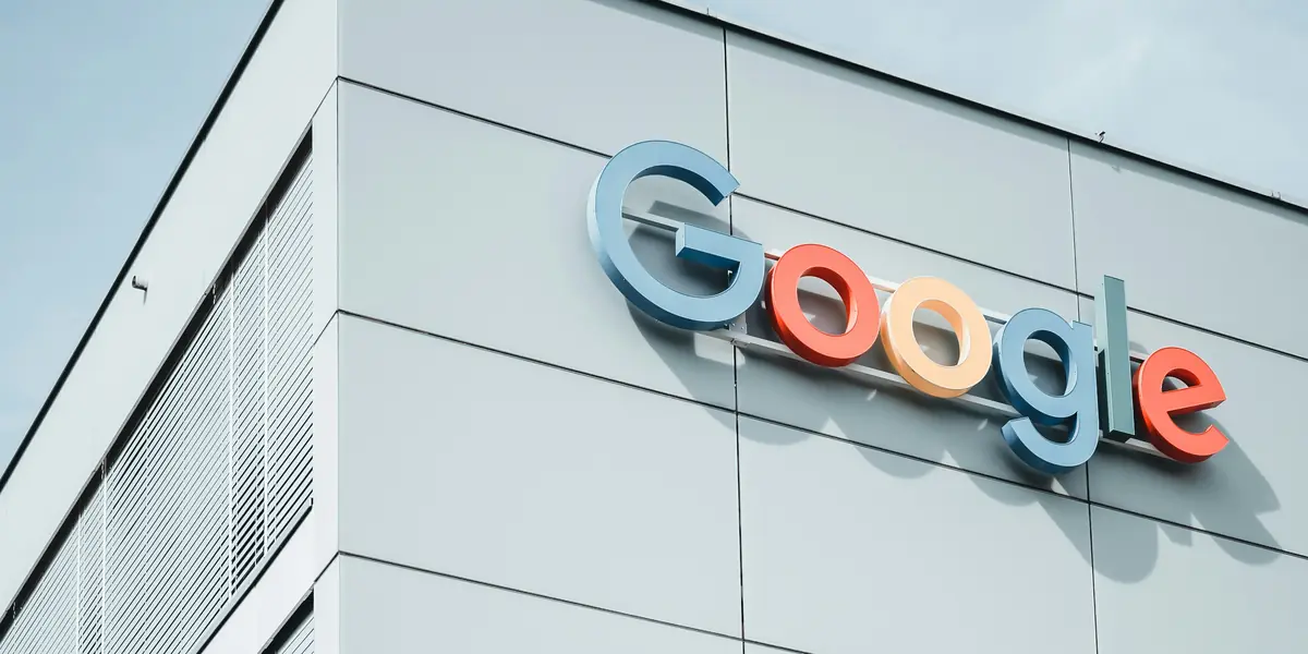 Sigla Google montată pe fațada albă a unei clădiri de birouri, fotografiată de jos