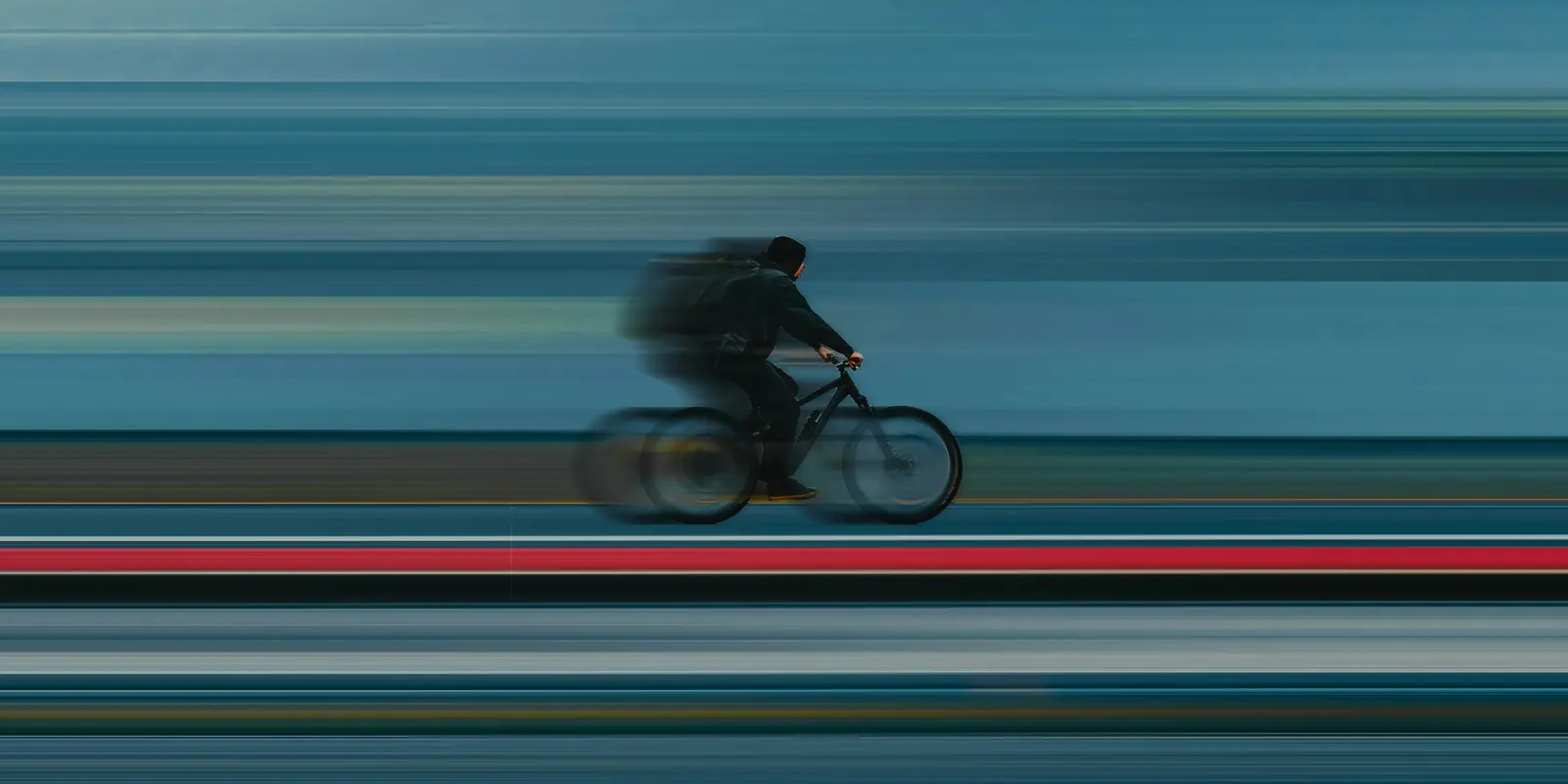 A cyclist crossing the frame at speed, the background pulled into horizontal streaks