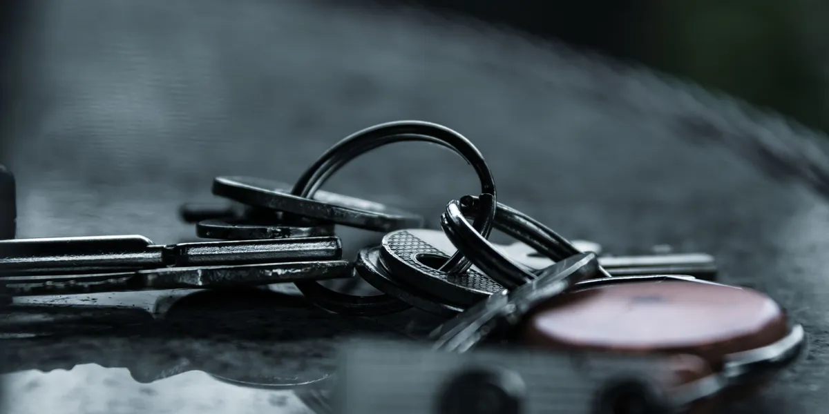 A bunch of metal keys resting on a dark, reflective surface