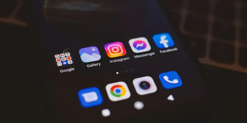 Smartphone screen in low light with the Instagram, Messenger and Facebook app icons on the top row