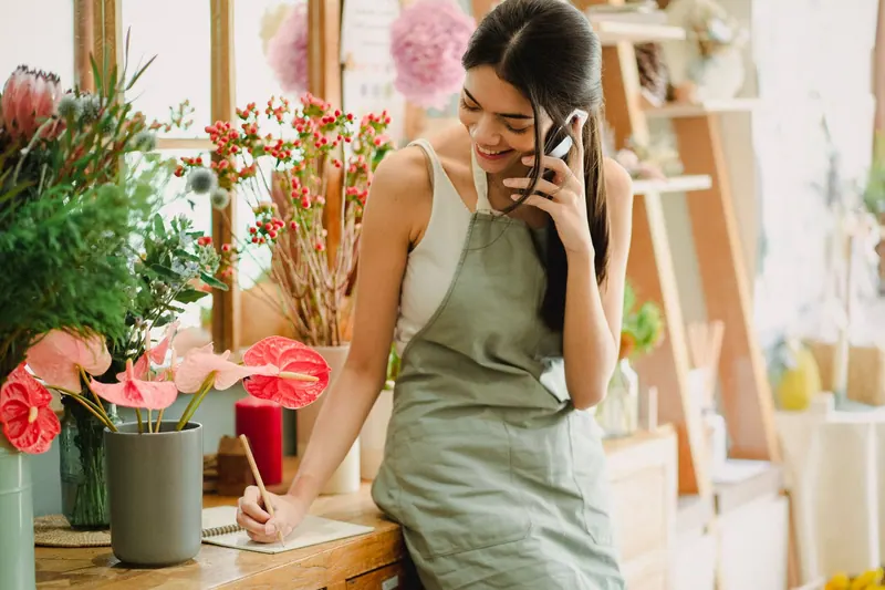 A florist owner smiling as she talks on the phone in her shop